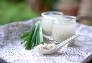 Barley water or soup in glasses and cooked pearly barley on spoon with pandan leaves clipart