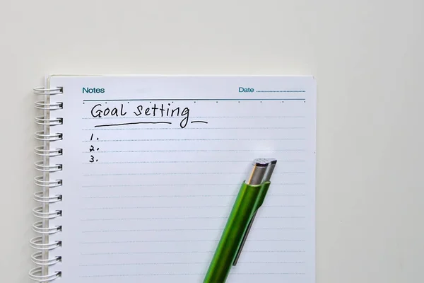 Goals setting to be written on a notebook with a green pen — Stock Photo, Image