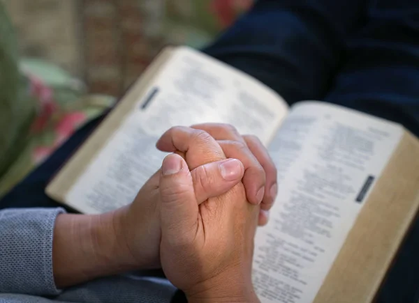 Gebet: Männliche Hände auf offener Bibel aneinander geklammert — Stockfoto