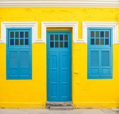 Sarı duvarda mavi kapı ve pencereler