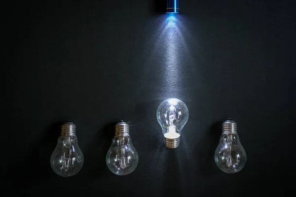 Flashlight shine on one light bulb — Stock Photo, Image