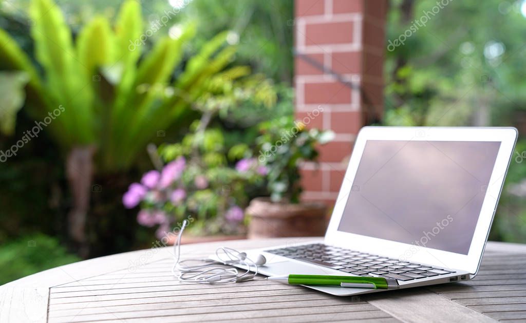 Laptop with ear phones, garden background