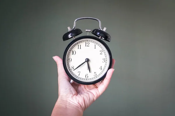 Mão segurando um relógio de alarme — Fotografia de Stock