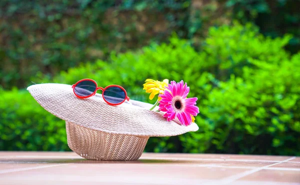 Strand mössa med solglasögon och Gerbera daisy blommor — Stockfoto