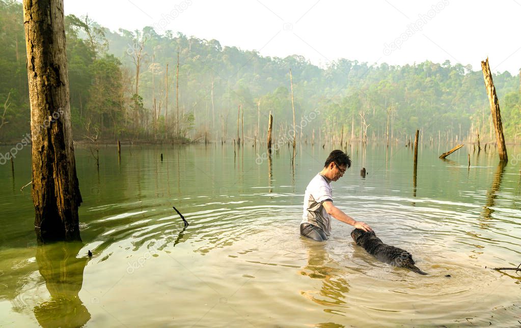 Man and dog playing and swimming in a lake.