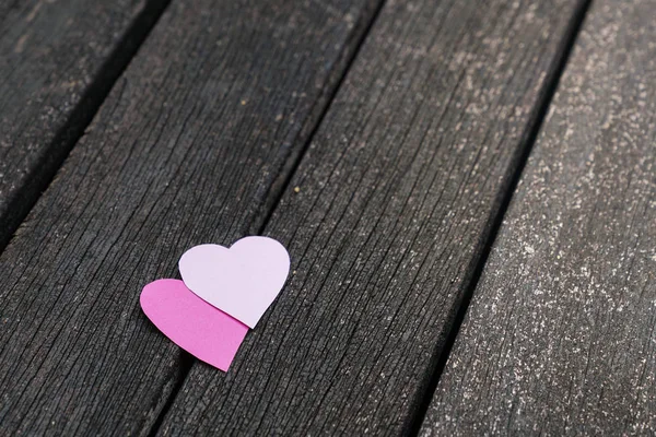 Love concept: Two paper hearts on a dark wood board — Stock Photo, Image