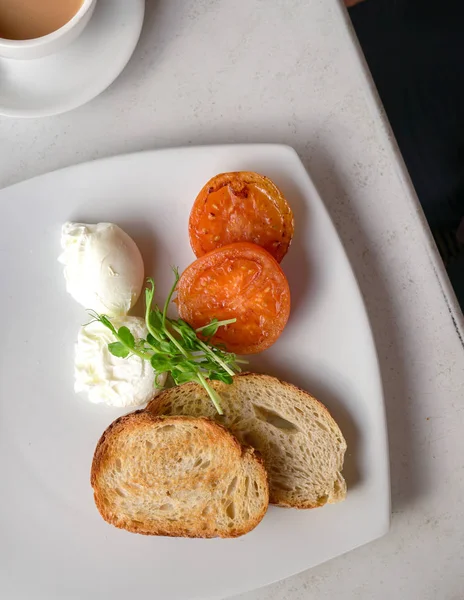 ポーチドエッグ、トマト、トーストパンを使用したヘルシーな朝食を提供しています。T — ストック写真