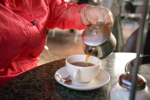 Pouring black tea into a white cup — Stock Photo, Image