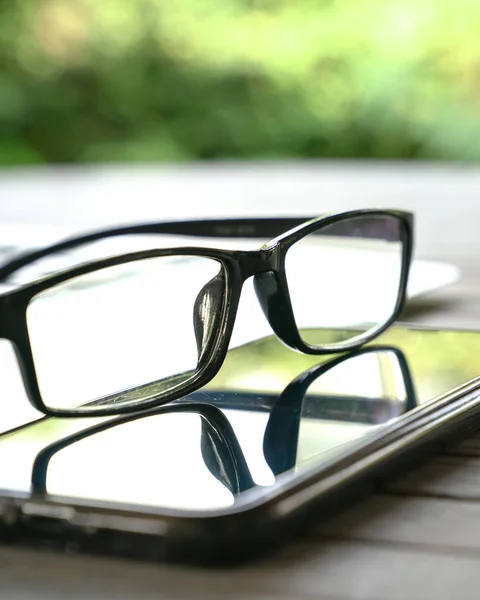 Reading glasses on top of cell phone with copy space — Stock Photo, Image