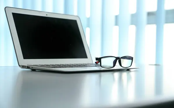Stół biurowy z notebookiem i okularami do czytania. Odbiór spac — Zdjęcie stockowe