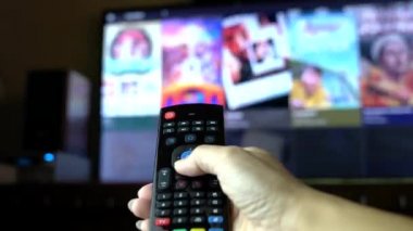 Uzaktan kumandayla televizyondaki film ya da televizyon programlarını izliyorsun. Evde ya da TV 'de konsept izlemek. Erkek parmaklarının yakın görüntüsü.