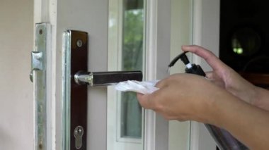 Kadın dezenfektanla kapı kolunu temizleyip siliyor. Coronavirüs veya covid-19 kavramından korunma.