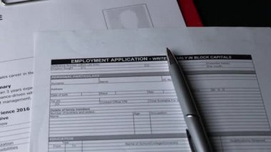 İş Başvurusu Formu, özgeçmişin üstünde, ofis masasında. Kaydırma atışı.