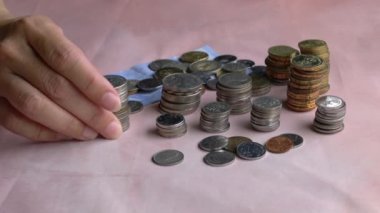 Yatırım konsepti için kenara ayrılan para ve madeni paraların bir kısmını kaldıran kadın..