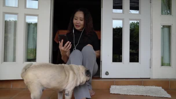 Kvinnan Pratar Mobilen Med Hörlurar Hemmiljö Med Mops Hund Begreppet — Stockvideo