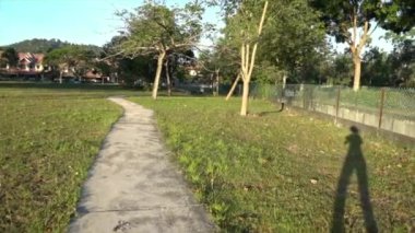 Yaya yolu olan güzel bir park ve üzerinde yürüyen uzun bir kadın gölgesi..