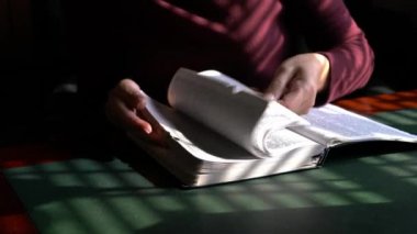 İncil 'i okurken sayfaları çeviren kadın. Kapalı ortam.