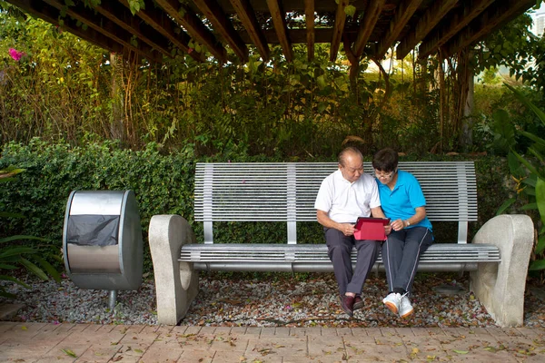 Elderly Chinese Couple Sitting Bench Reading Mobile Tablet Together — Stock Photo, Image