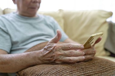 Yaşlı Asyalı adam cep telefonunu okuyor. 80 'li yaşlarında teknoloji meraklısı..