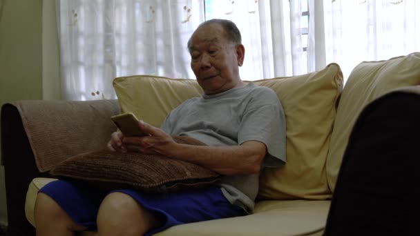 Пожилой Человек Сидящий Диване Читающий Свой Телефон — стоковое видео