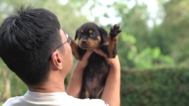 Yetişkin bir adam sevimli bir köpek yavrusu taşıyor ve yüzünü yalıyor..
