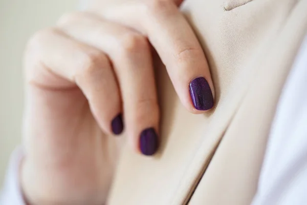 豪華なマニキュア 濃い紫色の柔らかい色のネイルポリッシュ クローズアップ写真 女性手上の簡単な背景のカジュアル服 — ストック写真