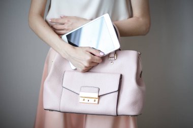 Bir kadının elindeki dijital elektronik tablet. Deri hafif pembe çanta, yaz zarif stili