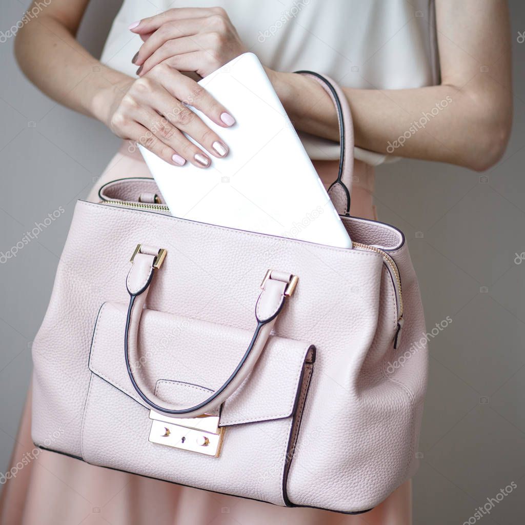 Digital electronic tablet on a woman's hands. Leather light pink handbag, summer elegant style