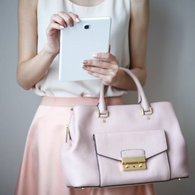 Bir kadının elindeki dijital elektronik tablet. Deri hafif pembe çanta, yaz zarif stili