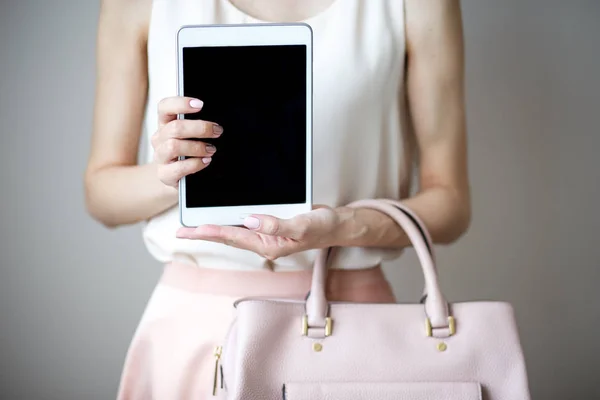 Digital electronic tablet on a woman\'s hands. Leather light pink handbag, summer elegant style