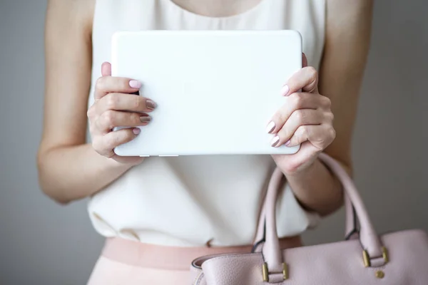 Digital electronic tablet on a woman\'s hands. Leather light pink handbag, summer elegant style