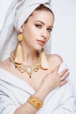 Genç kadın bir bornoz ve havlu onun kafa, moda altın takı, spa ve bakım portre, temiz doğal yüz, portre izole bir arka plan üzerinde