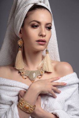 Genç kadın bir bornoz ve havlu onun kafa, moda altın takı, spa ve bakım portre, temiz doğal yüz, portre izole bir arka plan üzerinde