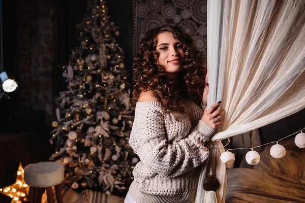 Pretty young woman in a room with christmas decoration. Winter mood, cozy home, scandinavian style