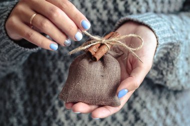Güzel manikür, pastel ihale renk oje, closeup fotoğraf. Eller basit bir hediye örgü gri arka plan üzerinde tutun.