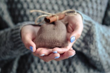 Güzel manikür, pastel ihale renk oje, closeup fotoğraf. Eller basit bir hediye örgü gri arka plan üzerinde tutun.