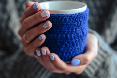 Güzel manikür, pastel ihale renk oje, closeup fotoğraf. Örgü mavi kapak bir kaba kadın el ele tutuşur