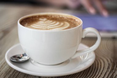 Genç kadın bir arka plan üzerinde ahşap bir masa üzerinde kahve dijital tablet ile çalışır