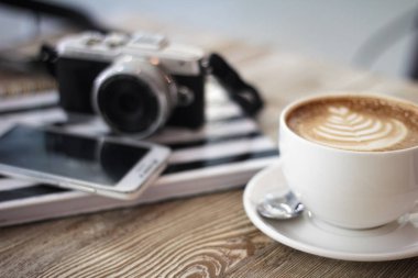 Kompakt dijital fotoğraf makinesi kahve ile ahşap bir masaya. Basit kompozisyon, yumuşak odak