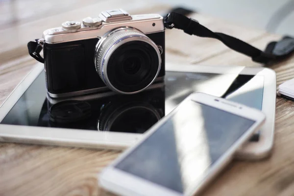 Compact digital photo camera on a wooden table with cup of coffee. Simple composition, soft focus