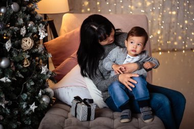 Rahat bir ceket ve kot pantolon onun büyükannesi ile Noel ağacının yanında oturan küçük oğlu 