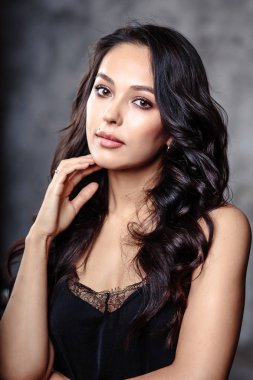 Güzel esmer kıvırcık ve kadın ile mükemmel cilt doğal makyaj closeup portresi. moda güzellik fotoğraf dokulu gri arka plan üzerinde