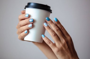 Güzel manikür, pastel ihale mavi renk oje, closeup fotoğraf. Eller bir plastik kahve fincanı basit arka plan üzerinde tutun. 