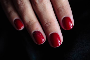 Güzel manikür, clssic kırmızı renk oje, closeup fotoğraf. Koyu kürk arka plan üzerinde eller 