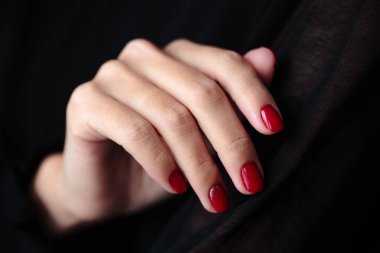 Güzel manikür, clssic kırmızı renk oje, closeup fotoğraf. Koyu kürk arka plan üzerinde eller 