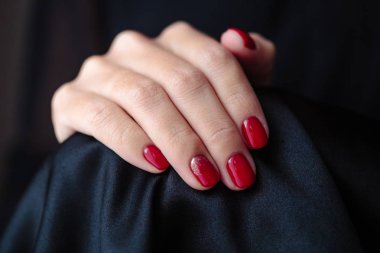 Güzel manikür, clssic kırmızı renk oje, closeup fotoğraf. Koyu kürk arka plan üzerinde eller 