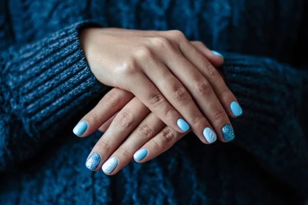 Gorgeous manicure, pastel tender blue color nail polish, closeup photo. Female hands over simple background