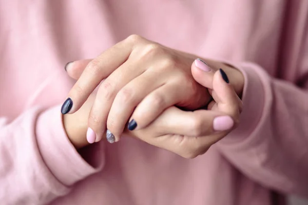 Gorgeous manicure, pastel tender pink color nail polish, closeup photo. Female hands over simple background