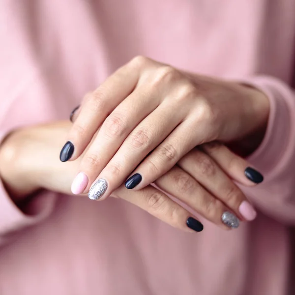 Gorgeous manicure, pastel tender pink color nail polish, closeup photo. Female hands over simple background