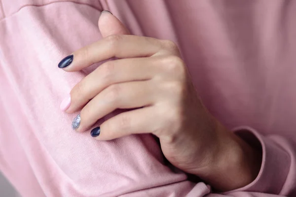Gorgeous manicure, pastel tender pink color nail polish, closeup photo. Female hands over simple background